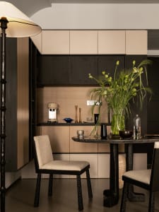 A modern, minimalist kitchen interior with wooden cabinets and a round dining table.
