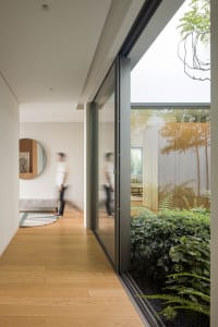 Modern residential entryway featuring wooden flooring and glass walls.
