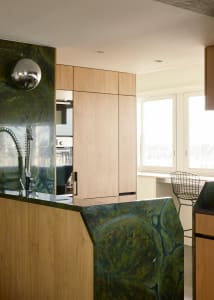 Modern kitchen with green marble countertops and light-colored wooden cabinets