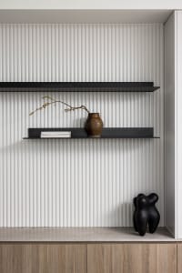 Modern shelves with metal shelves, a vase, a book, and a statue on a ribbed wall background.