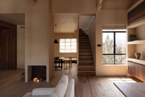 A minimalist indoor space featuring wooden stairs, brick walls, and concrete details.