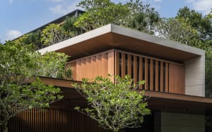 A modern residential building with wood and concrete exterior features a green, rooftop garden.