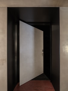 A modern entrance featuring a metallic grey panel, open to reveal an enclosed space.