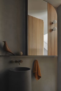 A modern bathroom featuring a concrete sink, wooden slat partition, and minimalist decor.