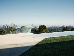 A modern residential pool with glass walls overlooking a cityscape.