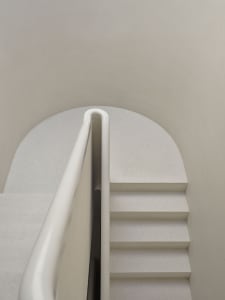 A minimalist concrete staircase with a white curved handrail.