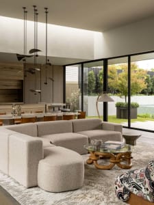 A modern living room featuring a large, textured fabric sofa and a round, wooden coffee table.