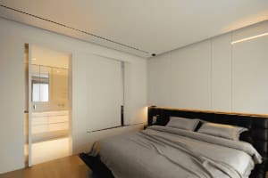 Modern bedroom with white walls and neutral bedding.