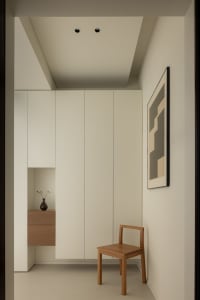 Minimalist living room with neutral tones and a wooden chair.