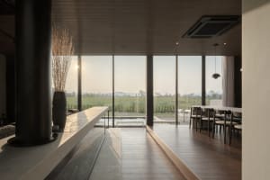 A modern dining room featuring a glass wall and minimalist furniture, providing a serene view of the landscape outside.