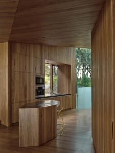 Modern kitchen with wooden cabinets and island, featuring stainless steel appliances and a large window.