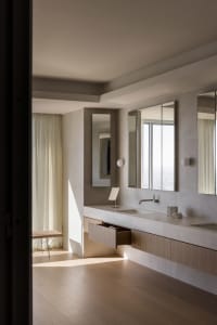 Modern minimalist bathroom featuring concrete walls, a floating wooden vanity, and large mirrors.