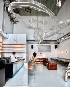 A modern restaurant with a metal and glass ceiling art installation