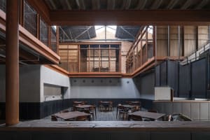 Industrial-style restaurant with concrete walls and floors, featuring concrete tables and chairs.