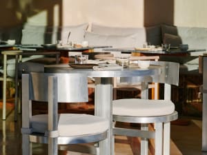A modern restaurant dining area featuring metal furniture, round tables, and minimalistic interior design.
