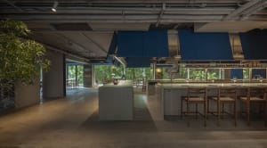 A modern restaurant kitchen with tile flooring and blue pendant lights hanging above a kitchen island.