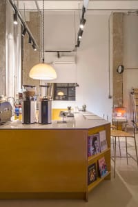 Interior of a coffee shop featuring a wooden counter with coffee grinders and seating area in the background.