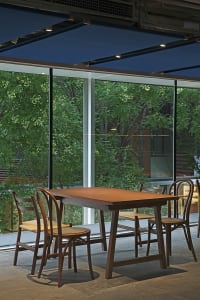 An industrial-style restaurant featuring wooden furniture and a glass exterior.