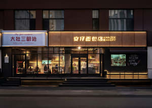 A modern bakery storefront with glass windows and illuminated signage.