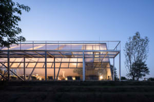 Modern glass exterior of an outdoor lounge with a glass roof and structural beams.