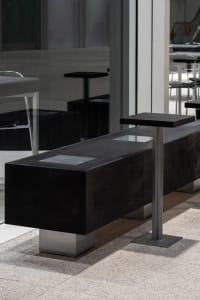 A modern public space furniture setup featuring concrete and metal elements.