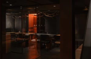Modern restaurant interior with wooden tables, concrete flooring, and minimalist design.