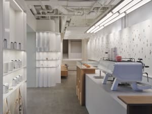 A minimalist coffee shop with white, concrete, and wooden elements.