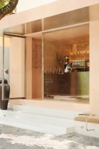 Glass and concrete exterior of a minimalist coffee shop with a logo reading 'KINYA'.