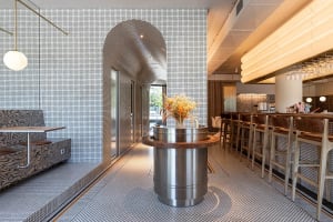 Modern cafe bar interior with metallic structures, ceramic tile floors, and wooden seating.