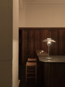 A minimalist interior with wooden elements, featuring a sleek lamp and a wooden counter.
