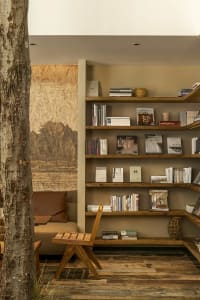 A minimalist library space featuring wooden bookshelves with various books and a wooden chair.