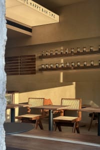 Industrial-style cafe with wooden seating and decor, featuring a menu board and shelves with coffee beans.