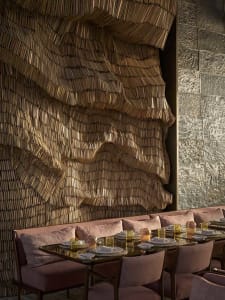 Modern restaurant interior with a textured, wavy wood wall and comfortable seating arrangement.