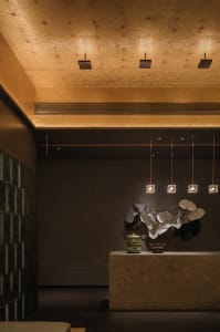 A sleek, modern hotel reception area featuring concrete walls, geometric lighting, and minimalist decor.