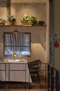 An industrial-style restaurant interior featuring concrete walls, rustic wood tables, and metal accents.
