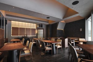 A modern restaurant interior featuring wooden tables and chairs, with a minimalist design aesthetic.