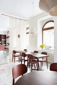 A minimalist cafe interior with wooden tables and chairs.