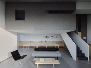 A modern minimalist living room with a concrete ceiling and minimalist furniture.