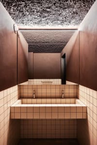 Public toilet with modern design featuring concrete walls and tiled floor