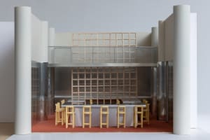 A modern restaurant bar with metal tables and wooden barstools.