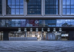 Modern storefront with glass facade, metal railings, and concrete elements.