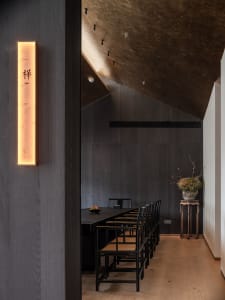 A minimalist restaurant interior with dark wood finishes and a sleek, modern design.