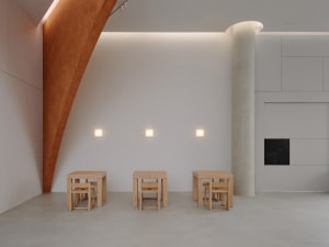 A minimalist room with wooden furniture and concrete flooring.