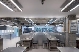 A modern hotpot restaurant interior with metallic counters and stools.