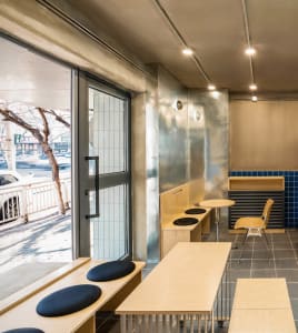 A modern cafe interior featuring minimalist design with wood elements and metal accents.