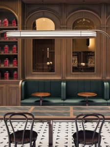A modern cafe interior with wooden seating, green leather booths, marble countertops, and a display of tea canisters.