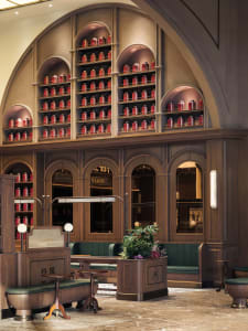 An elegant tea shop with wooden interior design, featuring arched shelves filled with red tea tins and comfortable seating ar