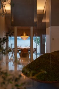 A modern elegant restaurant featuring metallic bronze lighting and minimalist concrete flooring.