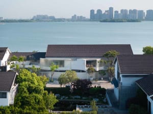 Modern house with glass, concrete, and wood features near a body of water