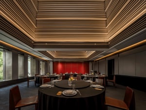 Modern restaurant interior with black tables, red backdrop, and muted color scheme.